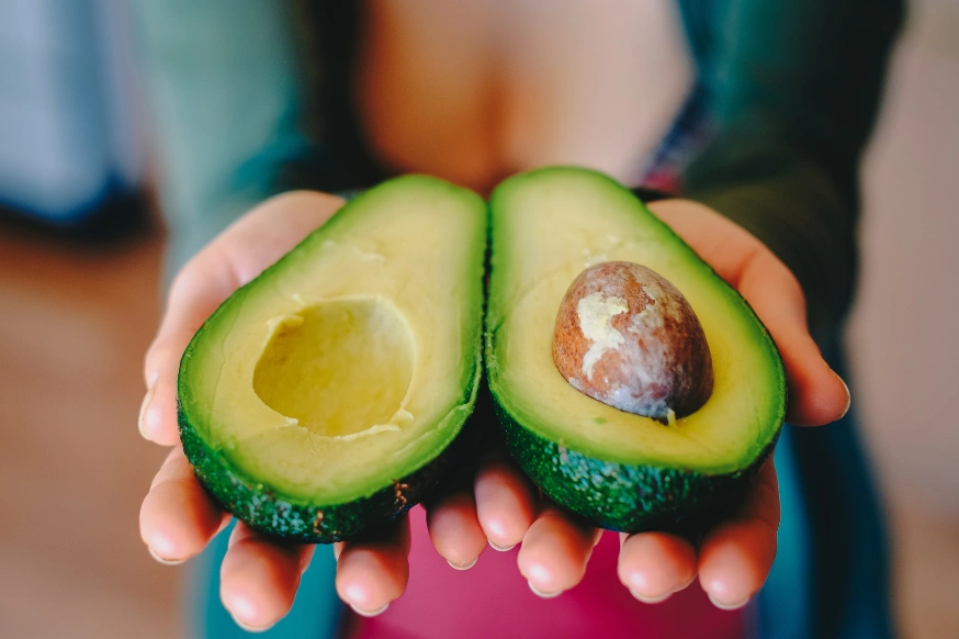 woman holding a sliced avocado